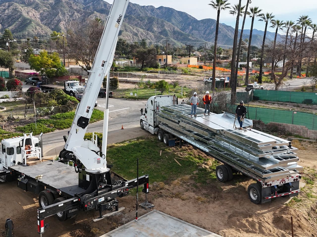 Light-gauge steel wall panels delivered by flatbed and crane to a rebuild site