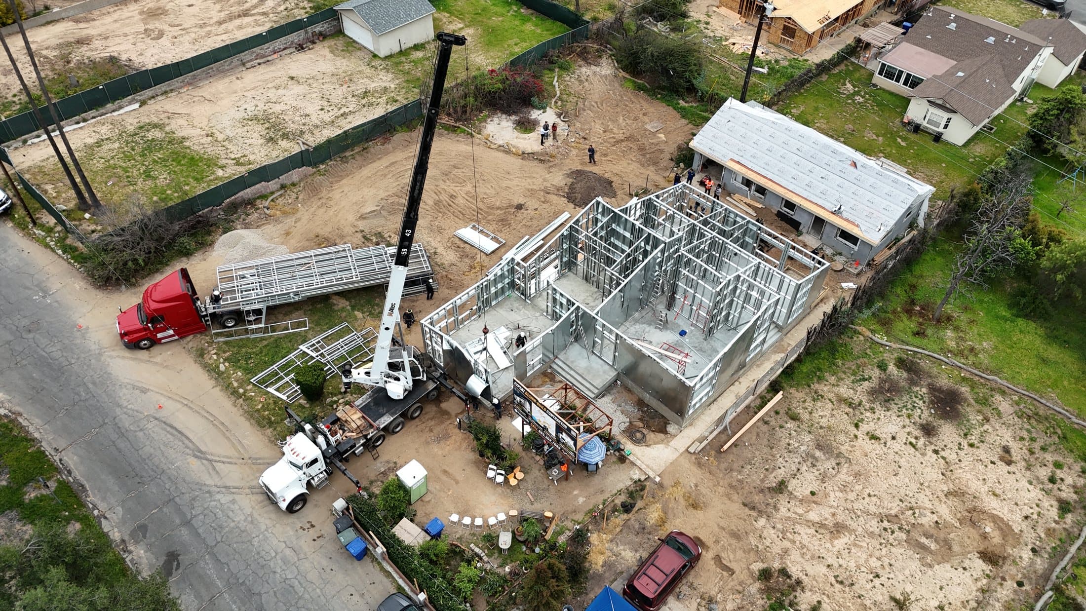 480 W Palm fire rebuild in Altadena, aerial view of the steel frame, crane and panel delivery rising in the burn zone