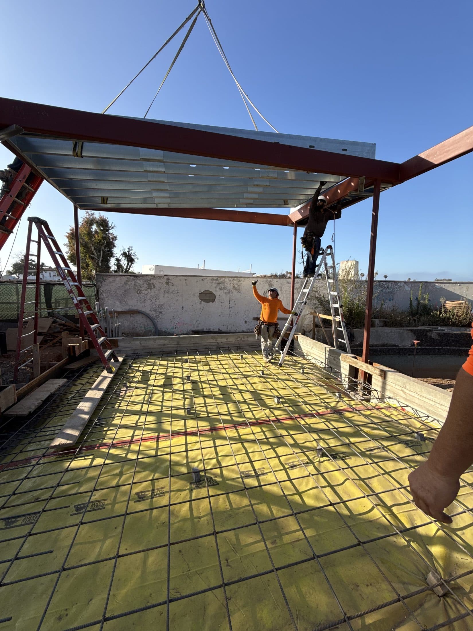 A crane lifts a structural steel beam into place at 777 Ocampo Drive, Pacific Palisades